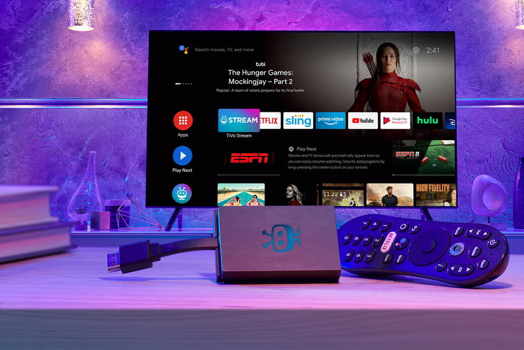 An image of the TiVo Stream 4K plus remote, sitting in front of a TV showing Android TV