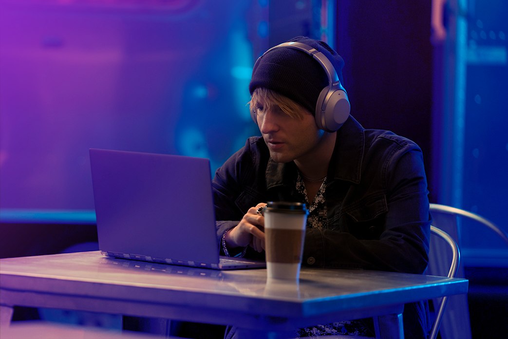 Image of man wearing headphones watching laptop