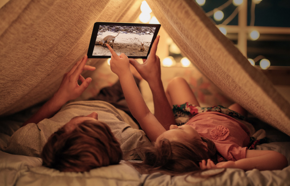 kids camping indoors with tablet playing show