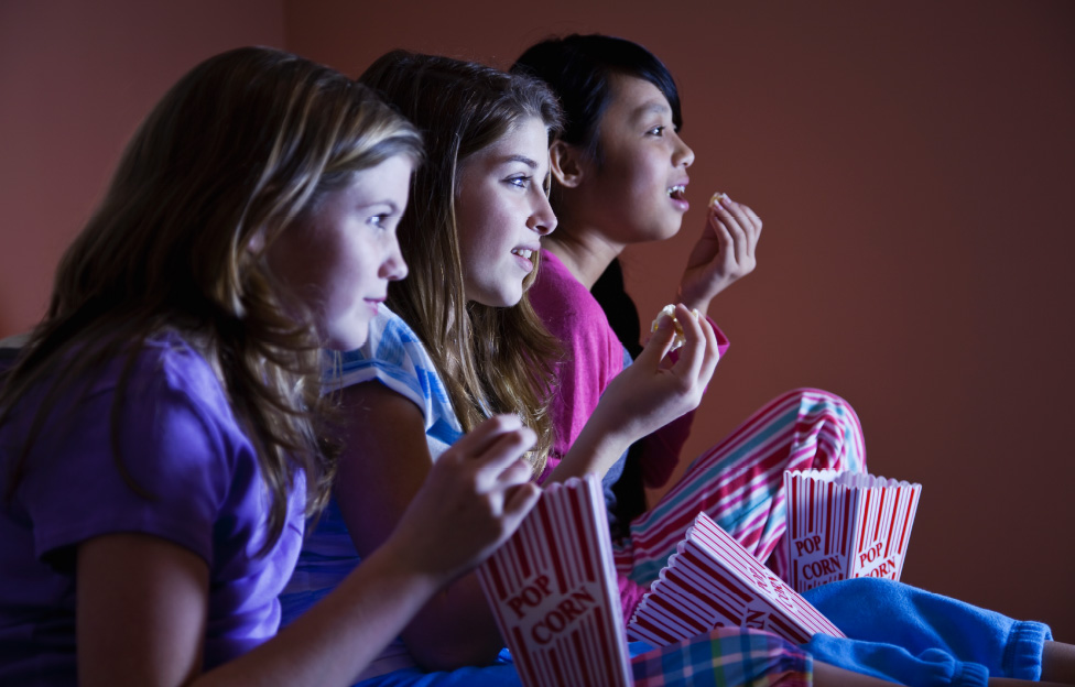women watching movie eating popcorn in their pajamas